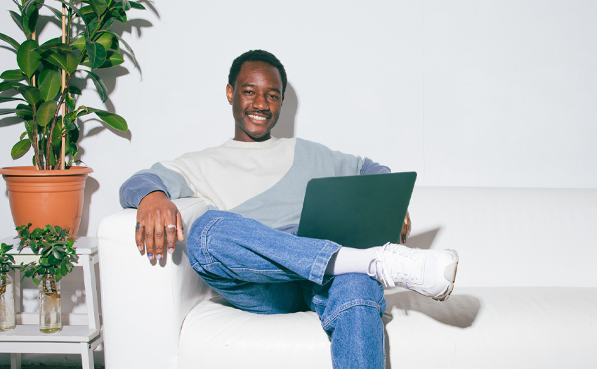Jongen op een bank met laptop glimlachend